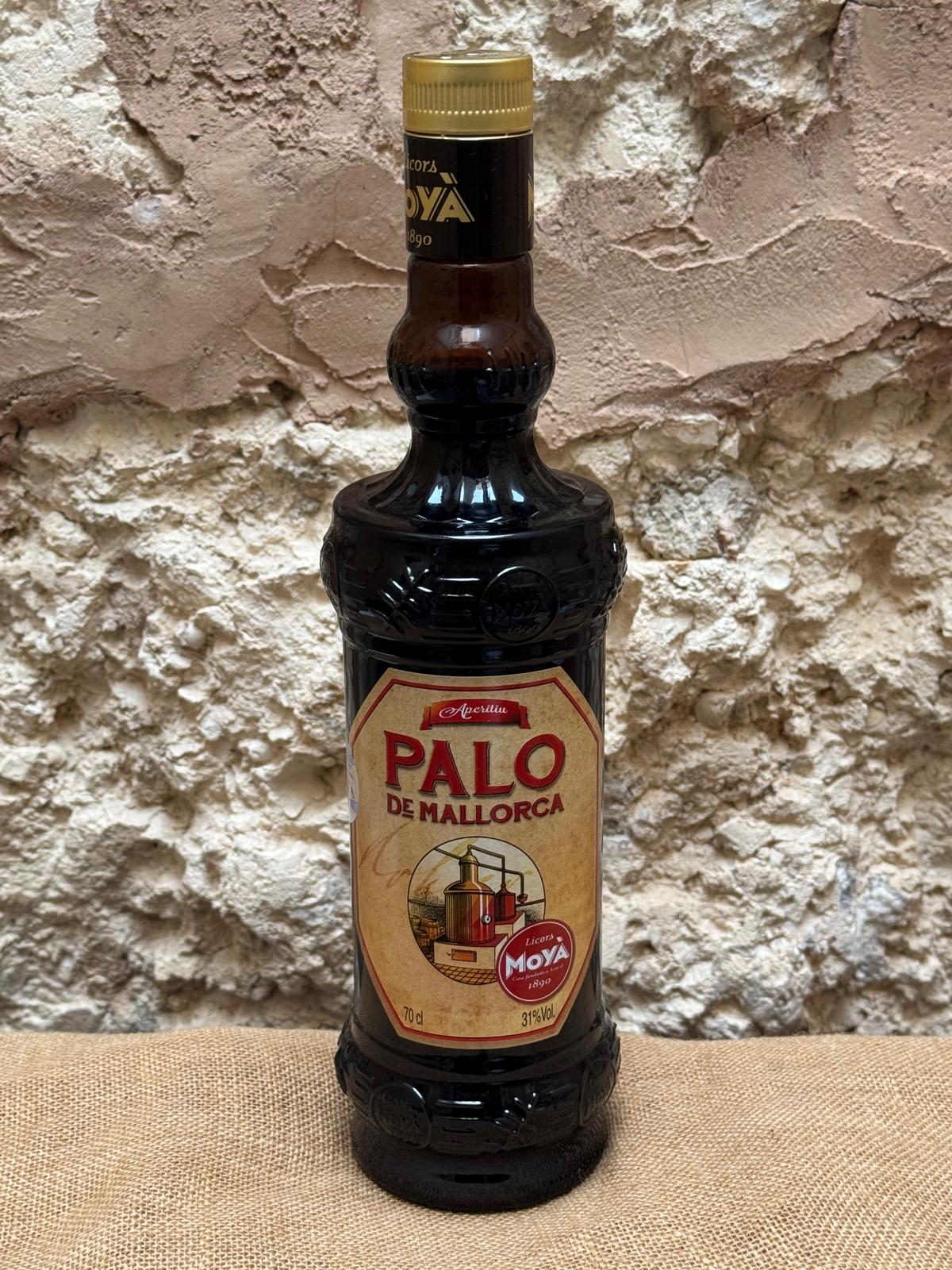 Licor Palo de Mallorca bottle with dark amber liquid and decorative label, set against a rustic wooden background.